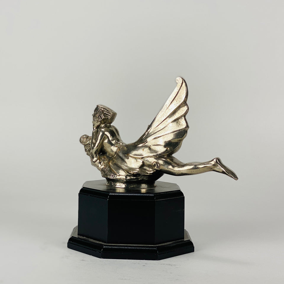 Wave rider Car bonnet mascot by Georges Delperier  in the form of a winged woman laying on her front in a casual pose riding on top of a wave, with very fine hand finished detail. Raised on an octagonal wooden plinth