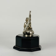 Wave rider Car bonnet mascot by Georges Delperier  in the form of a winged woman laying on her front in a casual pose riding on top of a wave, with very fine hand finished detail. Raised on an octagonal wooden plinth