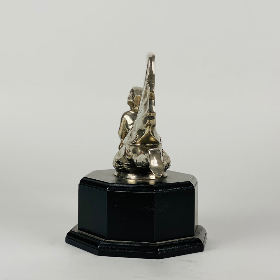 Wave rider Car bonnet mascot by Georges Delperier  in the form of a winged woman laying on her front in a casual pose riding on top of a wave, with very fine hand finished detail. Raised on an octagonal wooden plinth
