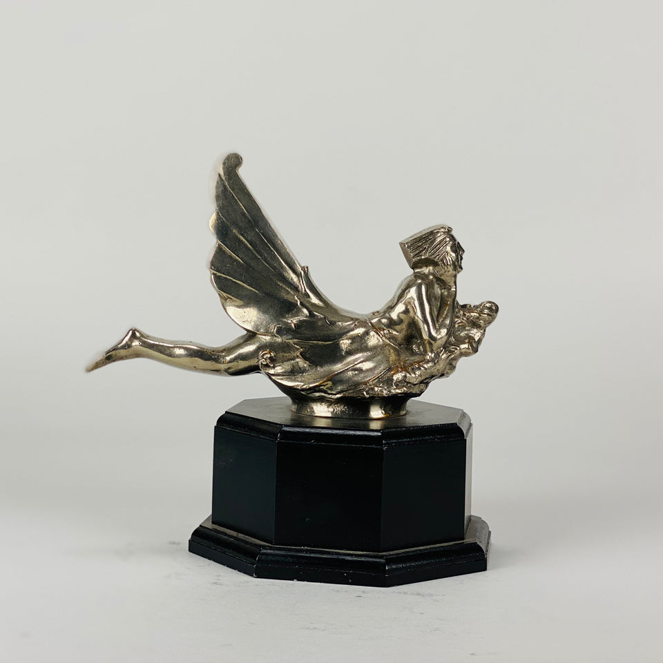 Wave rider Car bonnet mascot by Georges Delperier  in the form of a winged woman laying on her front in a casual pose riding on top of a wave, with very fine hand finished detail. Raised on an octagonal wooden plinth