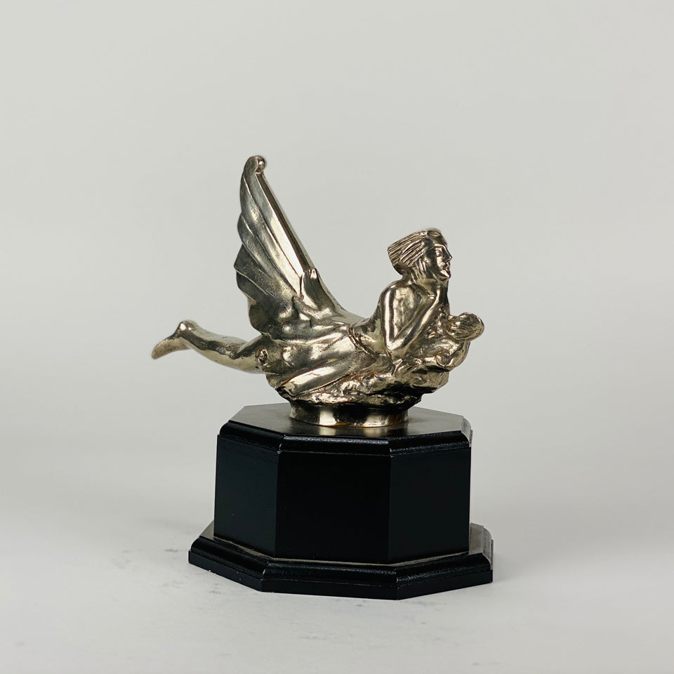 Wave rider Car bonnet mascot by Georges Delperier  in the form of a winged woman laying on her front in a casual pose riding on top of a wave, with very fine hand finished detail. Raised on an octagonal wooden plinth