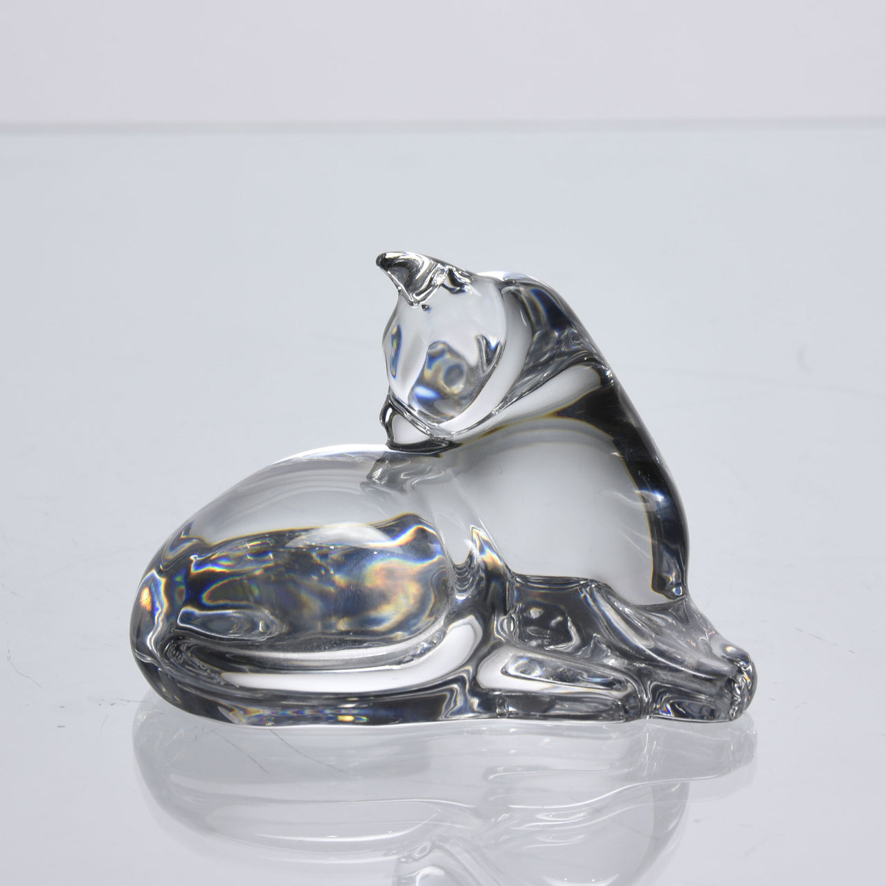 A charming mid 20th Century clear glass study of a relaxed cat in a reclining position grooming itself, with excellent smooth tactile surface, signed under base 