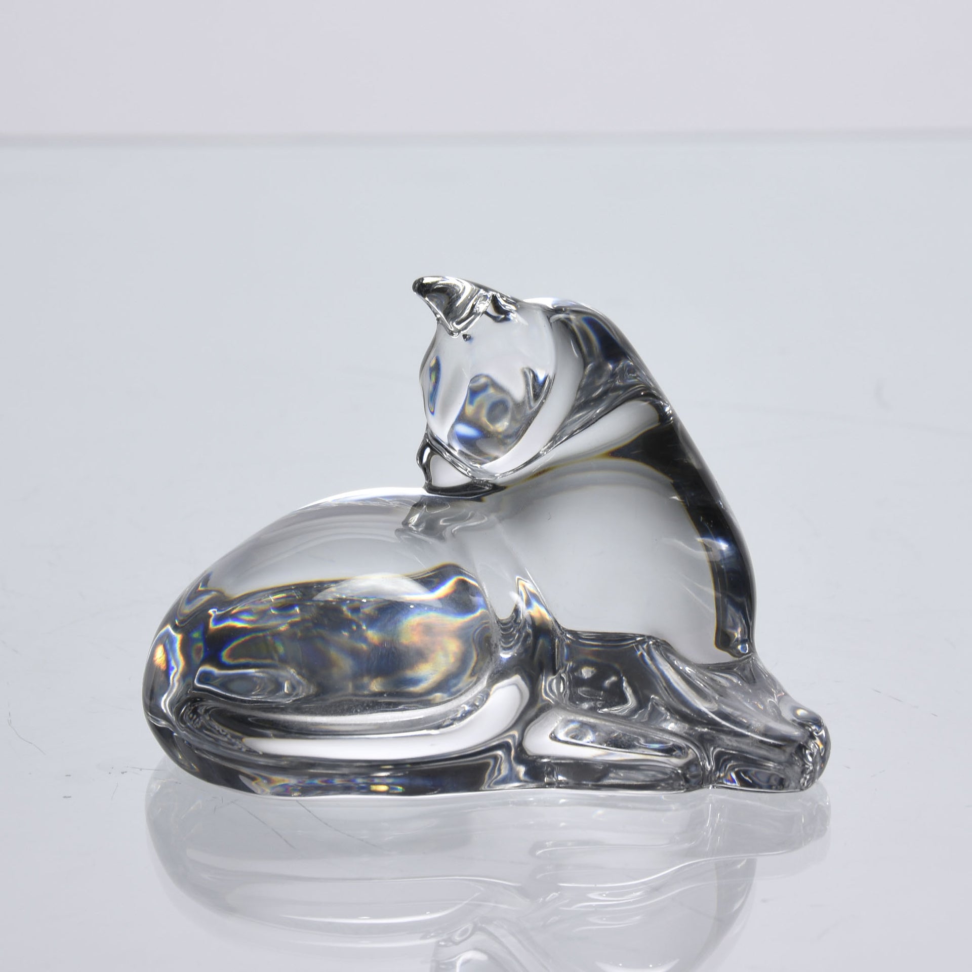 A charming mid 20th Century clear glass study of a relaxed cat in a reclining position grooming itself, with excellent smooth tactile surface, signed under base 