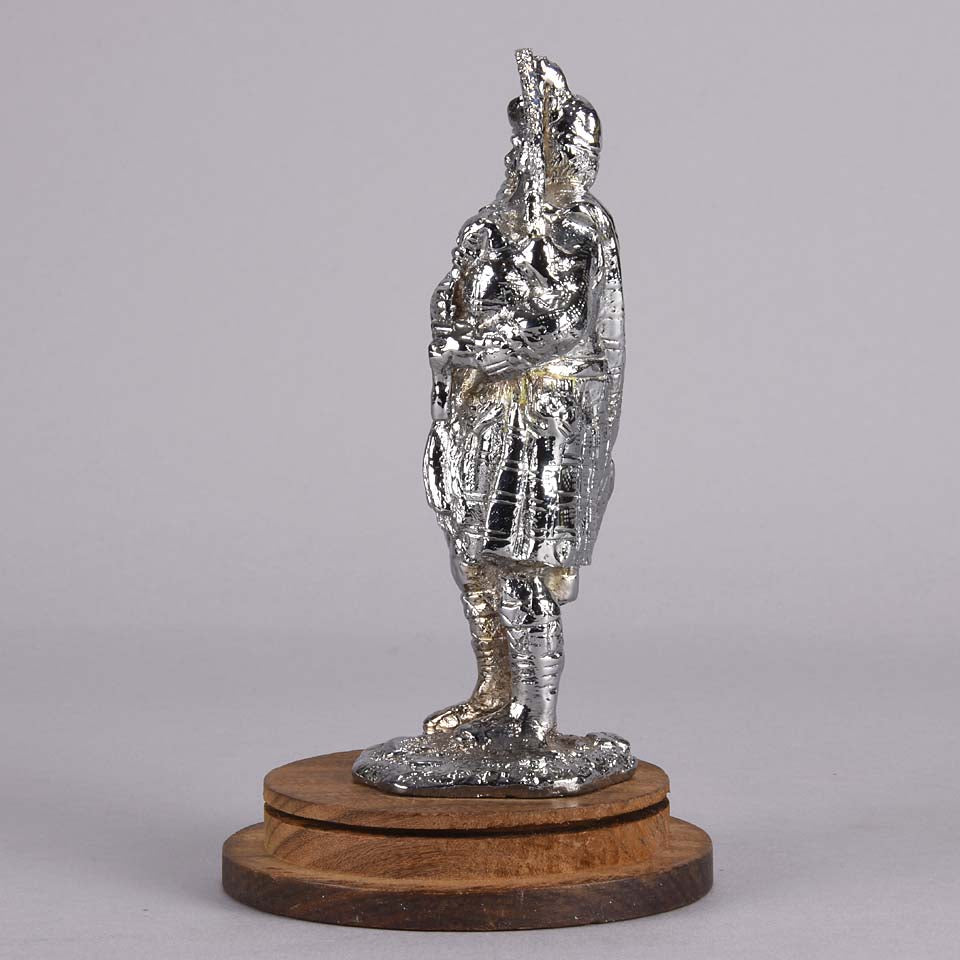 Bagpipes Car Bonet Mascot in the form of a Scotsman dressed in a kilt playing the bagpipes. Exhibiting a well polished surface and fine hand finished detail it is raised and fitted on a stepped circular stand