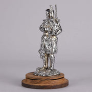Bagpipes Car Bonet Mascot in the form of a Scotsman dressed in a kilt playing the bagpipes. Exhibiting a well polished surface and fine hand finished detail it is raised and fitted on a stepped circular stand