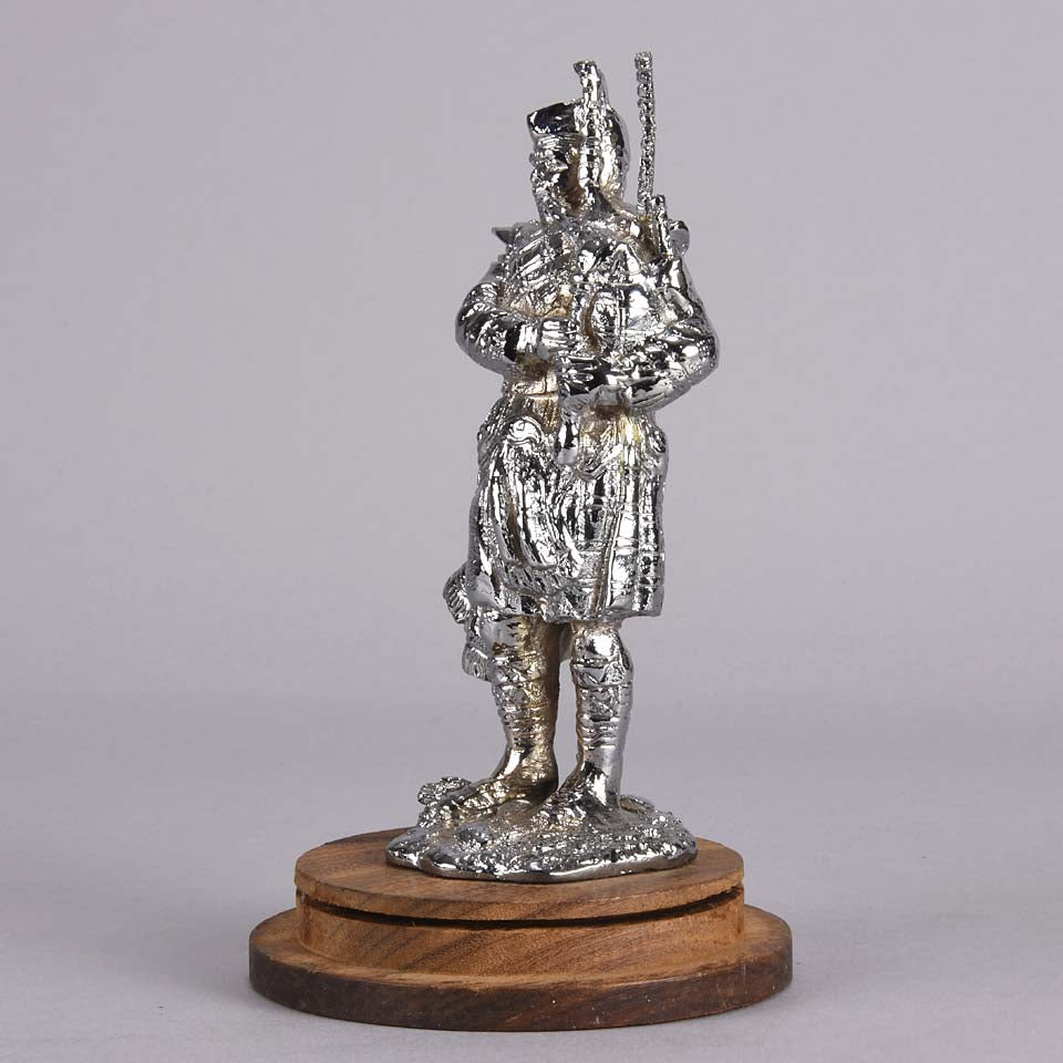 Bagpipes Car Bonet Mascot in the form of a Scotsman dressed in a kilt playing the bagpipes. Exhibiting a well polished surface and fine hand finished detail it is raised and fitted on a stepped circular stand