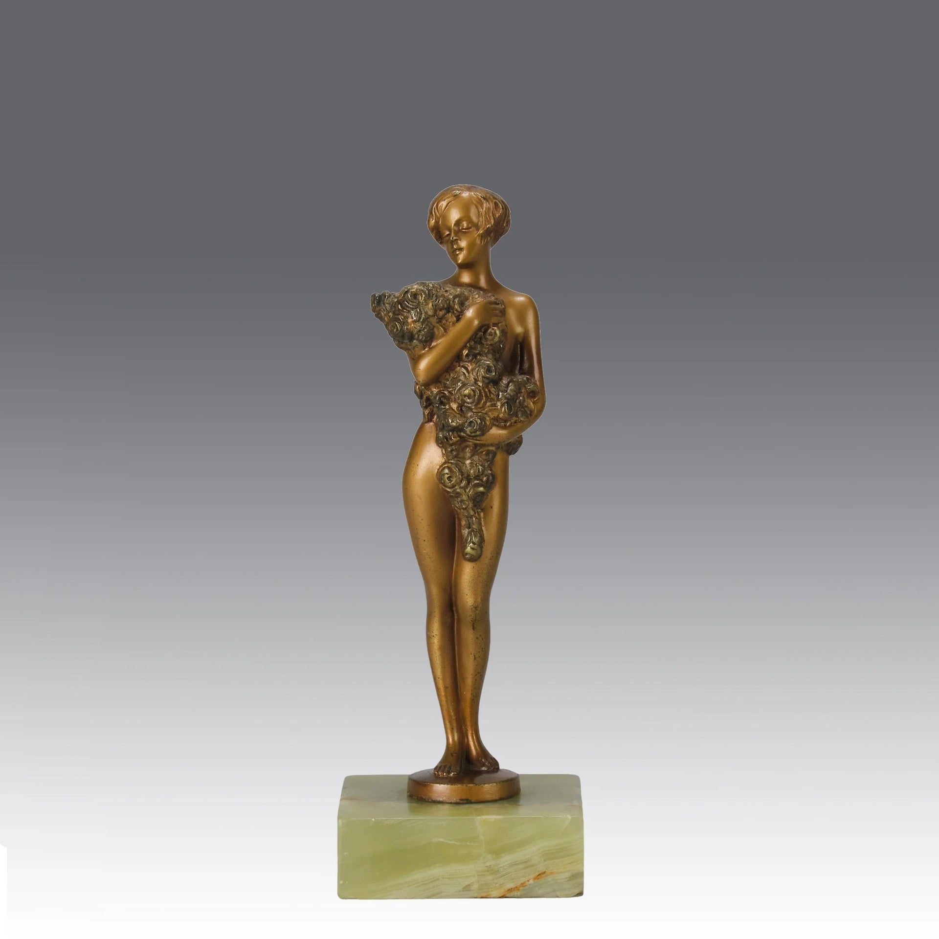 The Bouquet by Joseph Lorenzl an elegant early 20th Century Art Deco cold painted bronze figure of a young beauty holding a large bouquet of flowers covering her modesty raised on a green onyx base 