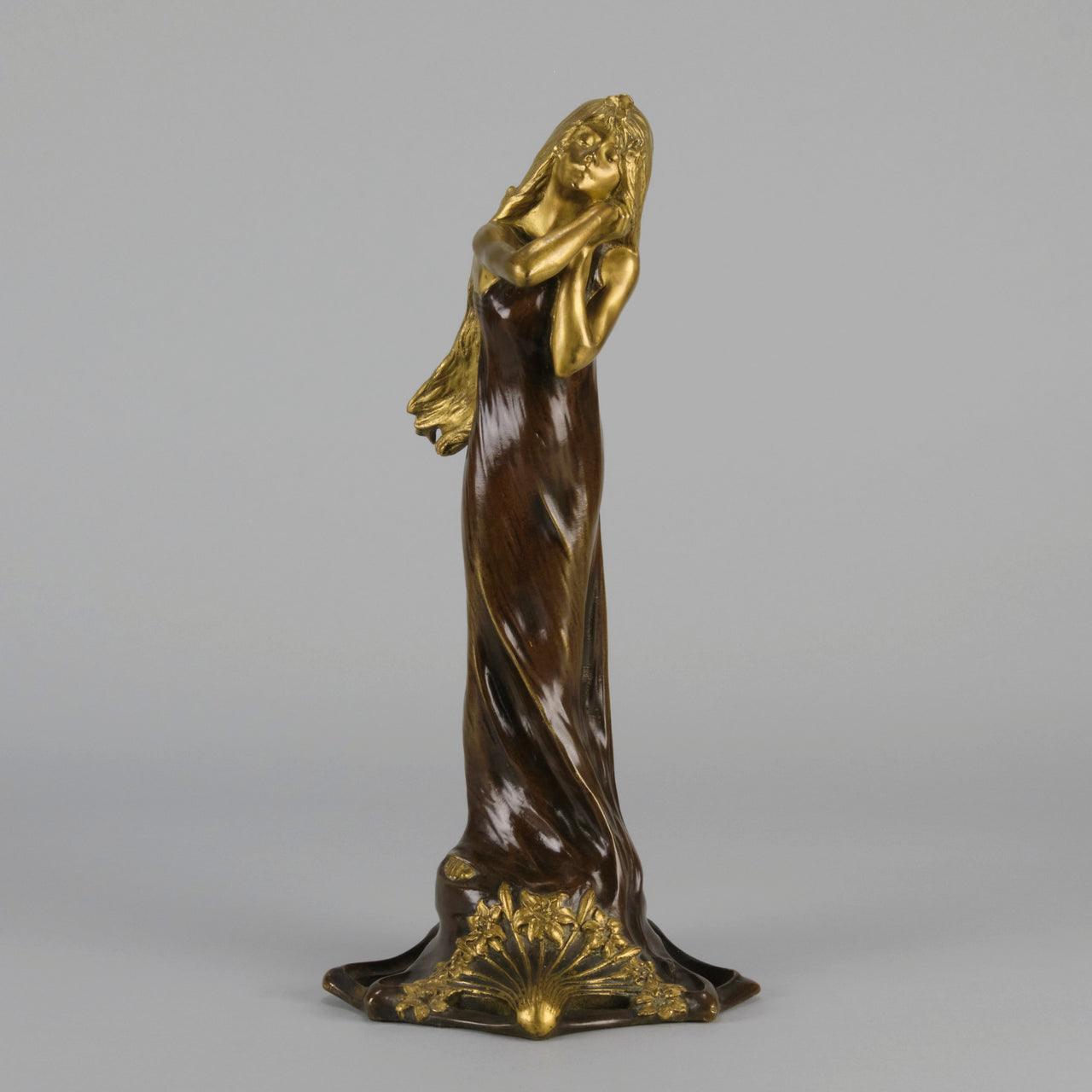 Jeune Femme by C Peyre A very fine Art Nouveau bronze study of a young beauty in coy pose, clothed in a long flowing skirt, her head and arms in gilt bronze to contrast with the rich brown colour of her clothes
