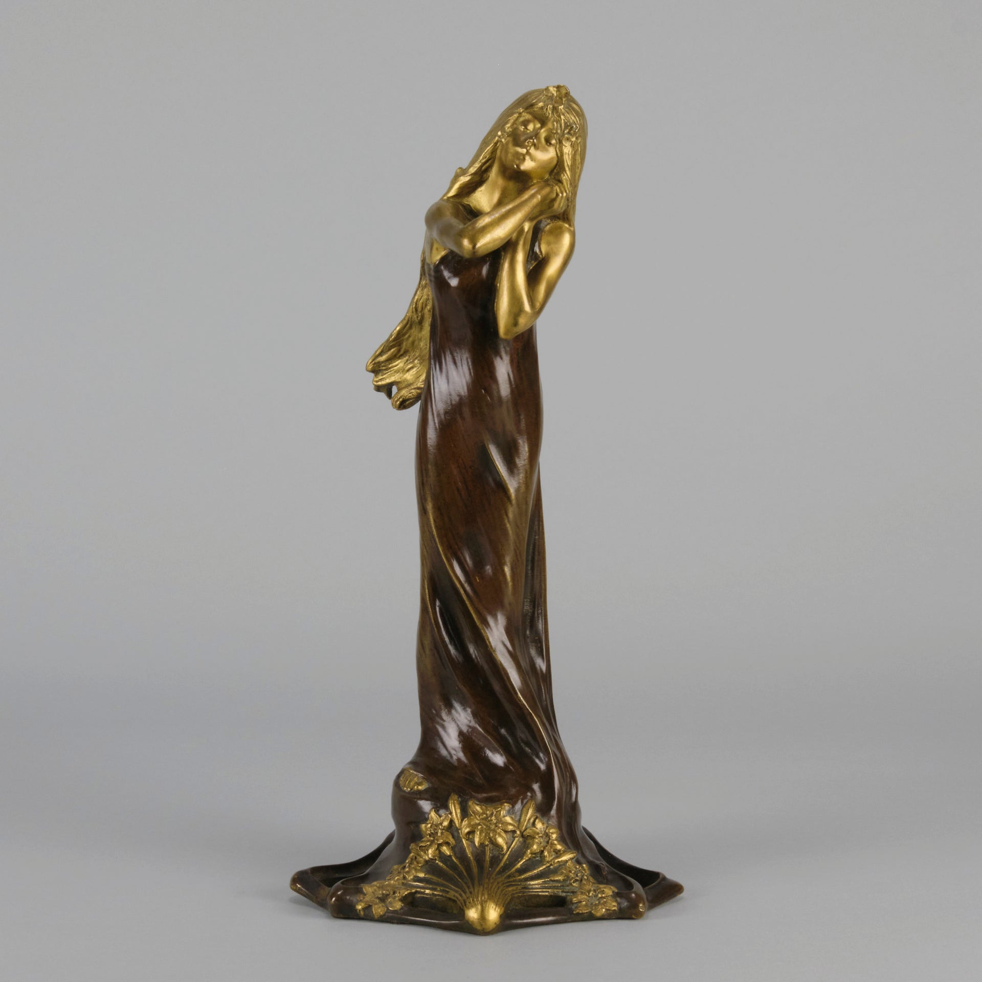 Jeune Femme by C Peyre A very fine Art Nouveau bronze study of a young beauty in coy pose, clothed in a long flowing skirt, her head and arms in gilt bronze to contrast with the rich brown colour of her clothes