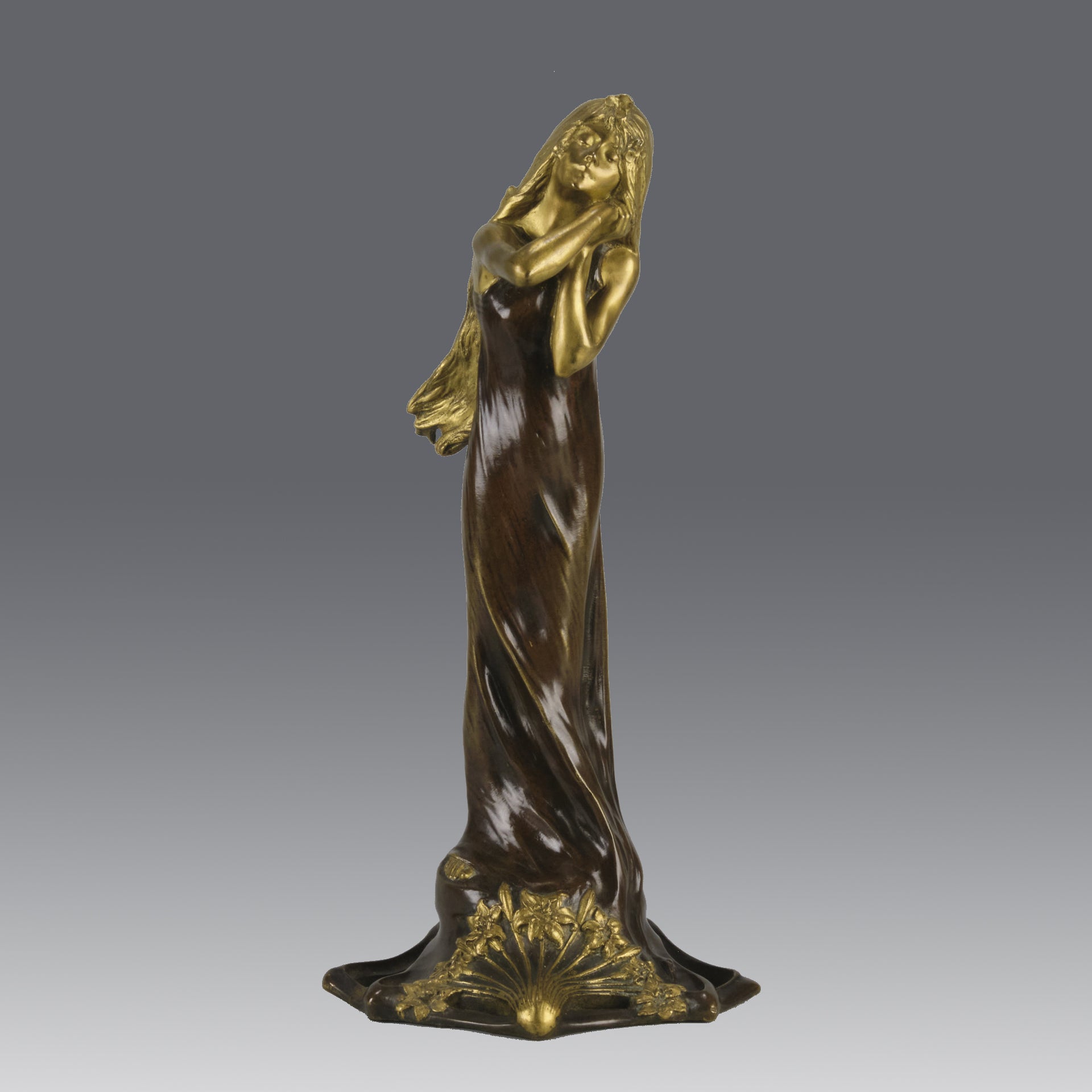 Jeune Femme by C Peyre A very fine Art Nouveau bronze study of a young beauty in coy pose, clothed in a long flowing skirt, her head and arms in gilt bronze to contrast with the rich brown colour of her clothes