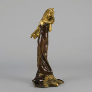 Jeune Femme by C Peyre A very fine Art Nouveau bronze study of a young beauty in coy pose, clothed in a long flowing skirt, her head and arms in gilt bronze to contrast with the rich brown colour of her clothes