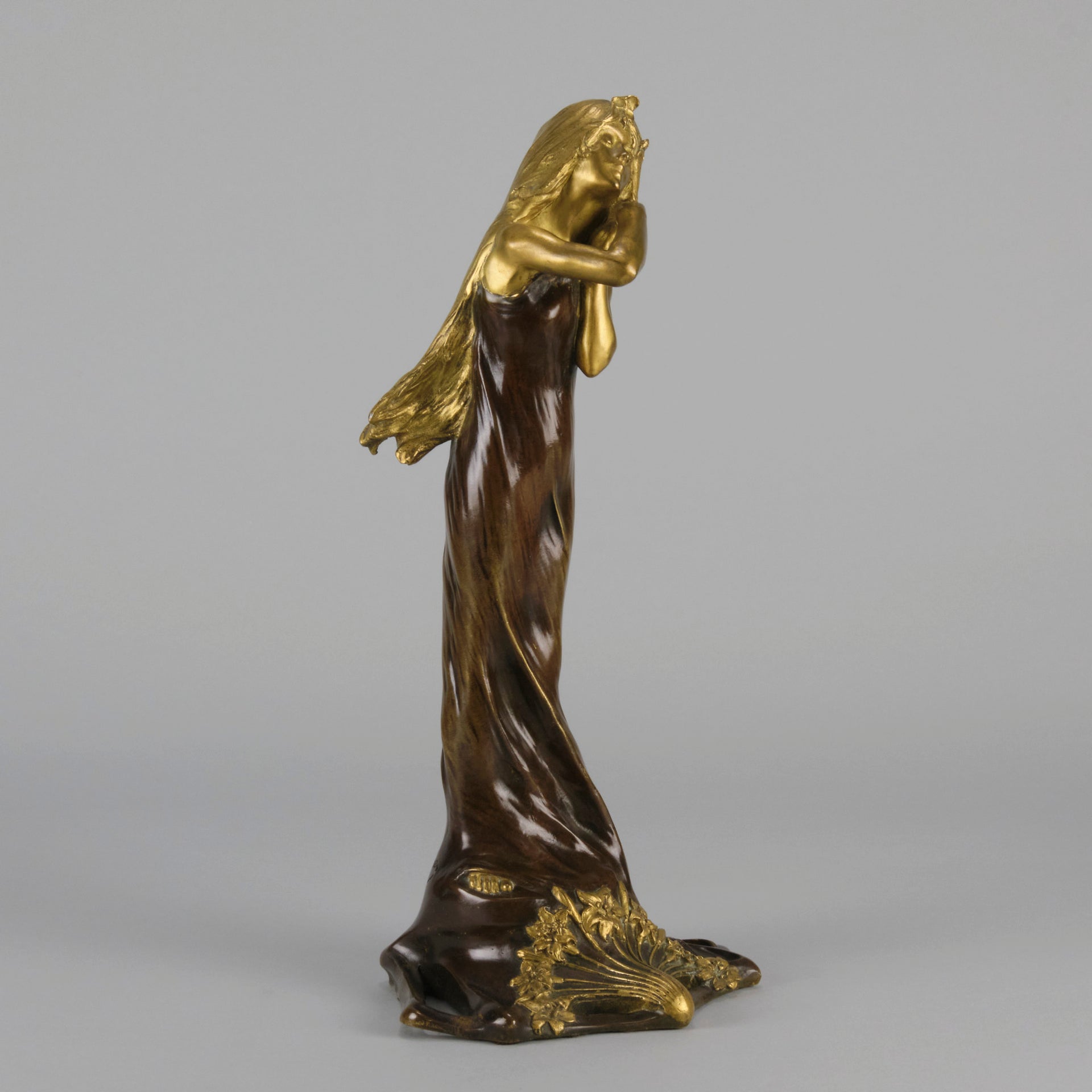 Jeune Femme by C Peyre A very fine Art Nouveau bronze study of a young beauty in coy pose, clothed in a long flowing skirt, her head and arms in gilt bronze to contrast with the rich brown colour of her clothes