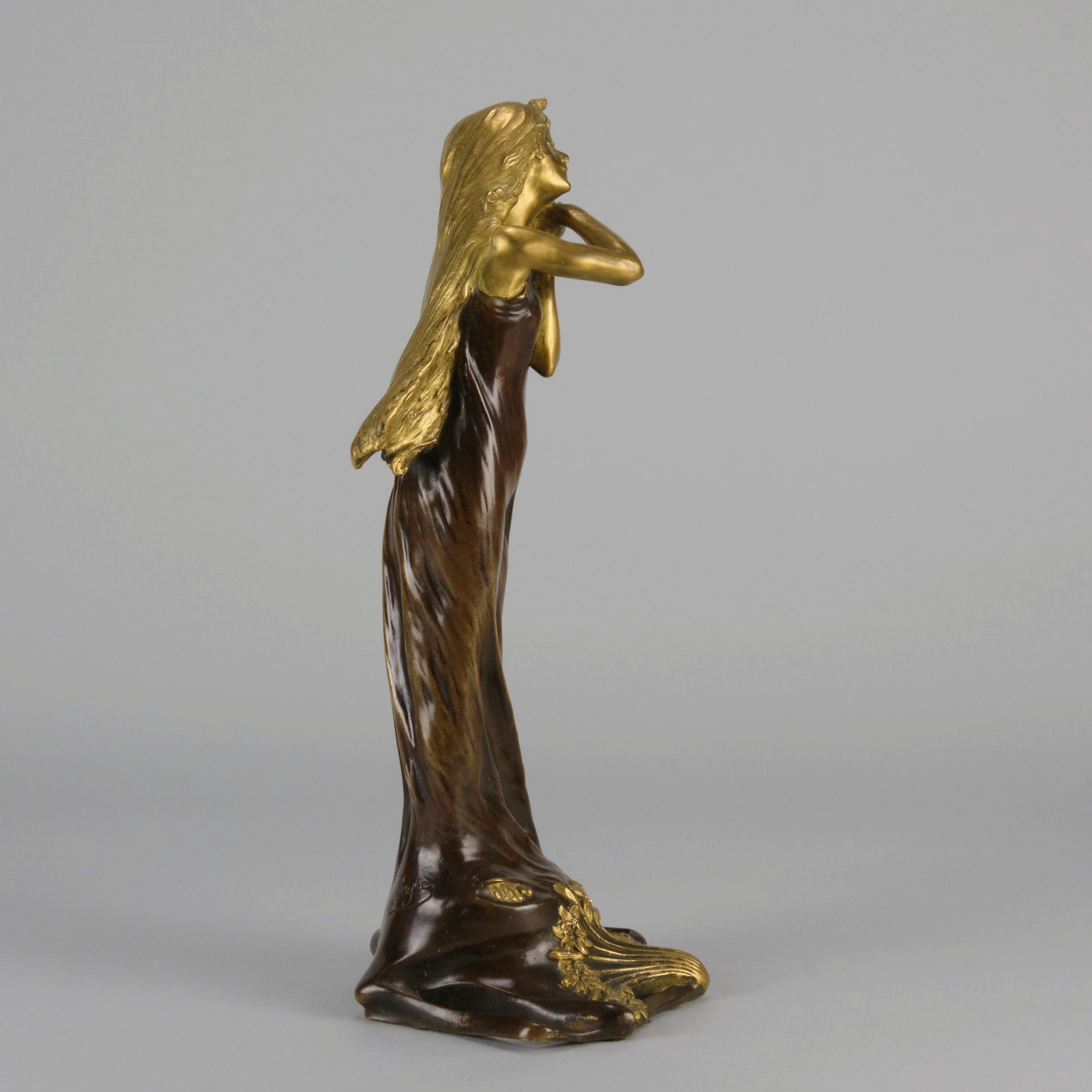 Jeune Femme by C Peyre A very fine Art Nouveau bronze study of a young beauty in coy pose, clothed in a long flowing skirt, her head and arms in gilt bronze to contrast with the rich brown colour of her clothes