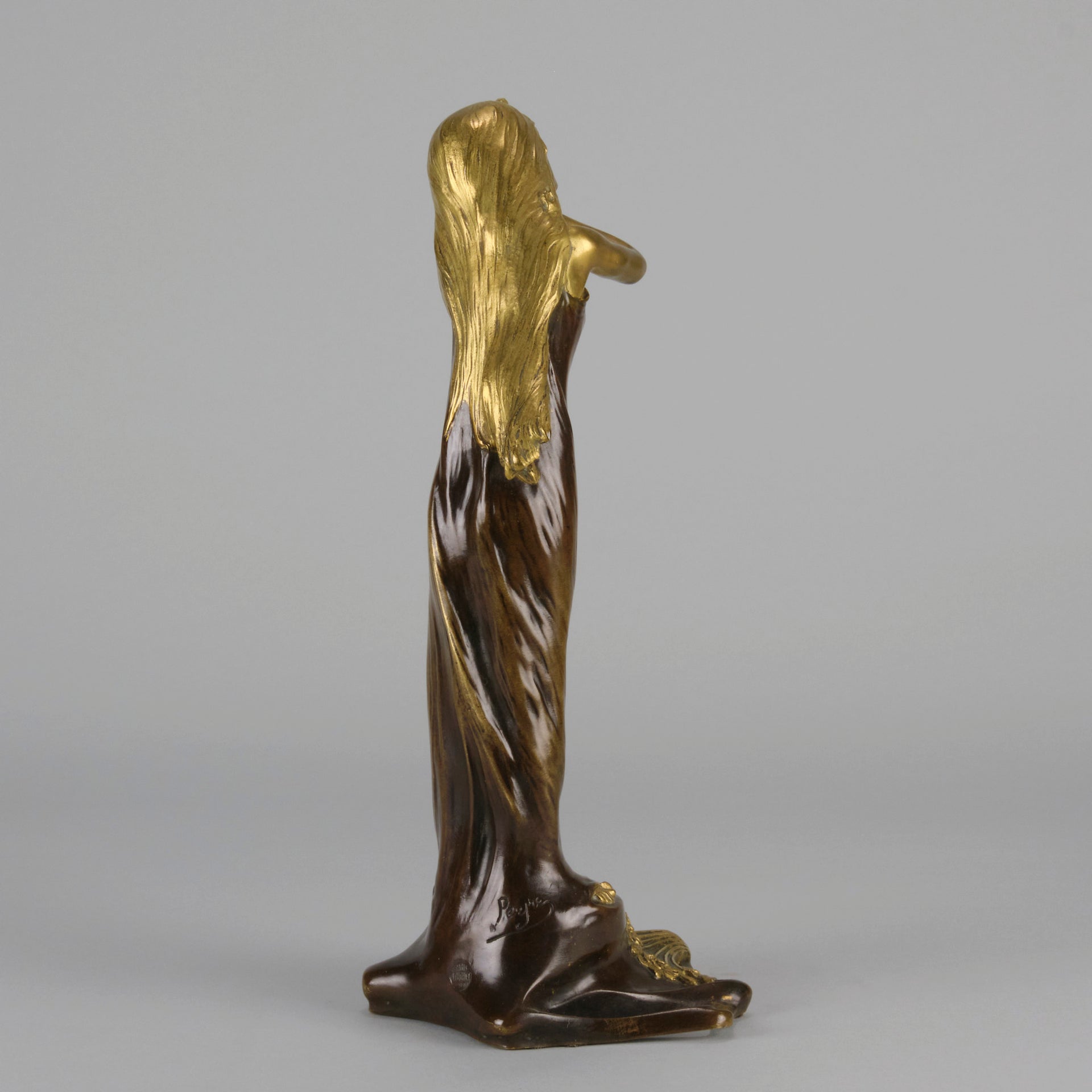 Jeune Femme by C Peyre A very fine Art Nouveau bronze study of a young beauty in coy pose, clothed in a long flowing skirt, her head and arms in gilt bronze to contrast with the rich brown colour of her clothes