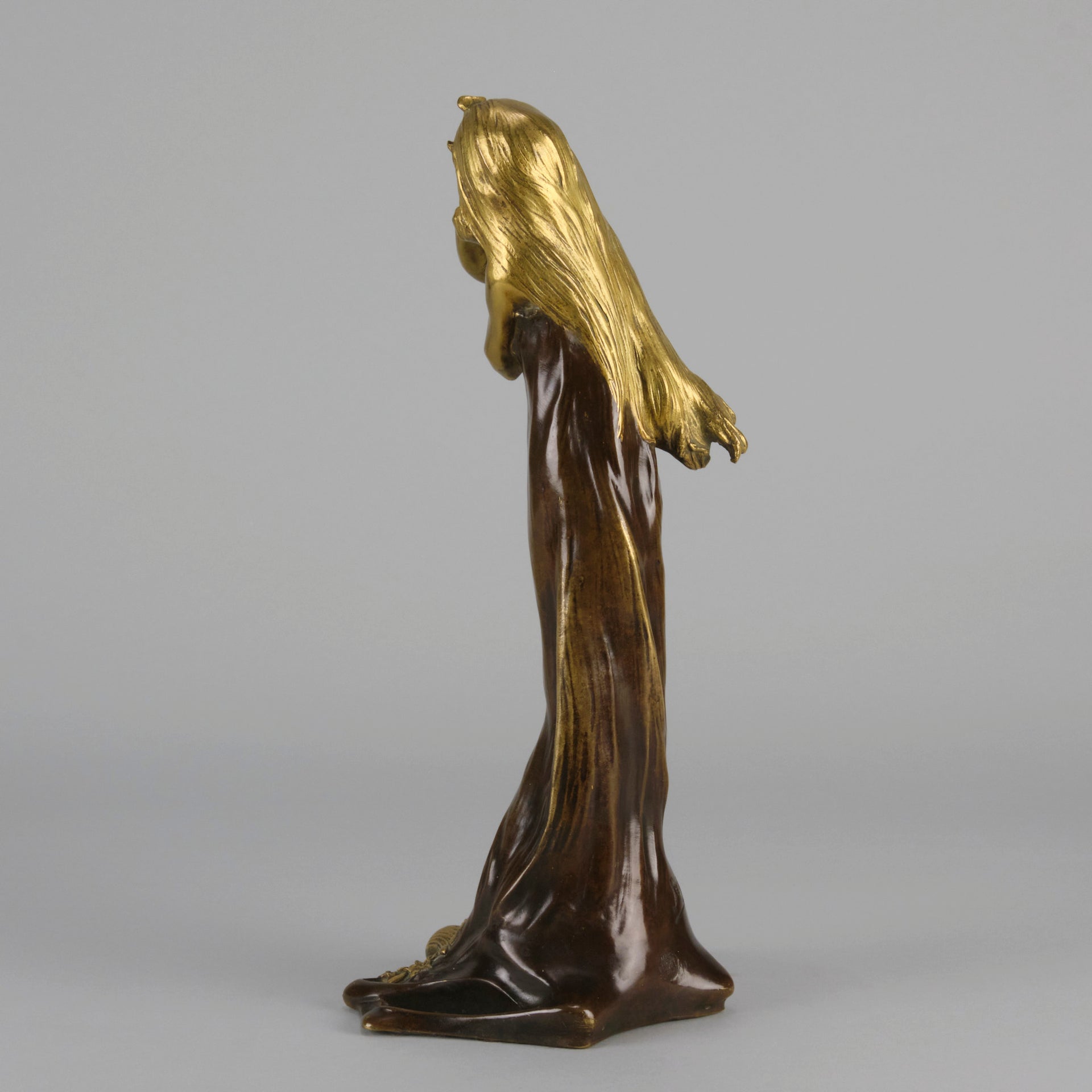 Jeune Femme by C Peyre A very fine Art Nouveau bronze study of a young beauty in coy pose, clothed in a long flowing skirt, her head and arms in gilt bronze to contrast with the rich brown colour of her clothes