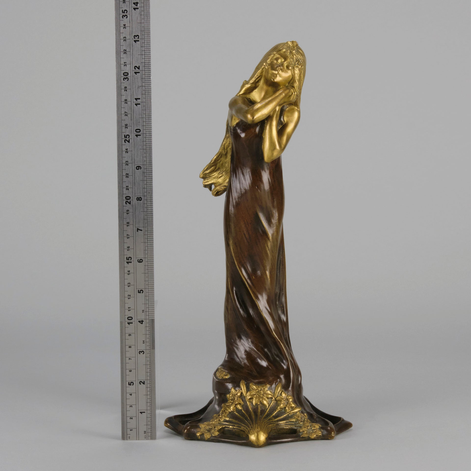 Jeune Femme by C Peyre A very fine Art Nouveau bronze study of a young beauty in coy pose, clothed in a long flowing skirt, her head and arms in gilt bronze to contrast with the rich brown colour of her clothes