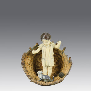 Girl & Cat with Basket - Bergman Bronze - A charming early 20th Century Austrian bronze group study of a young child and cat standing in a wicker basket playing with a ball of string - Hickmet Fine Arts