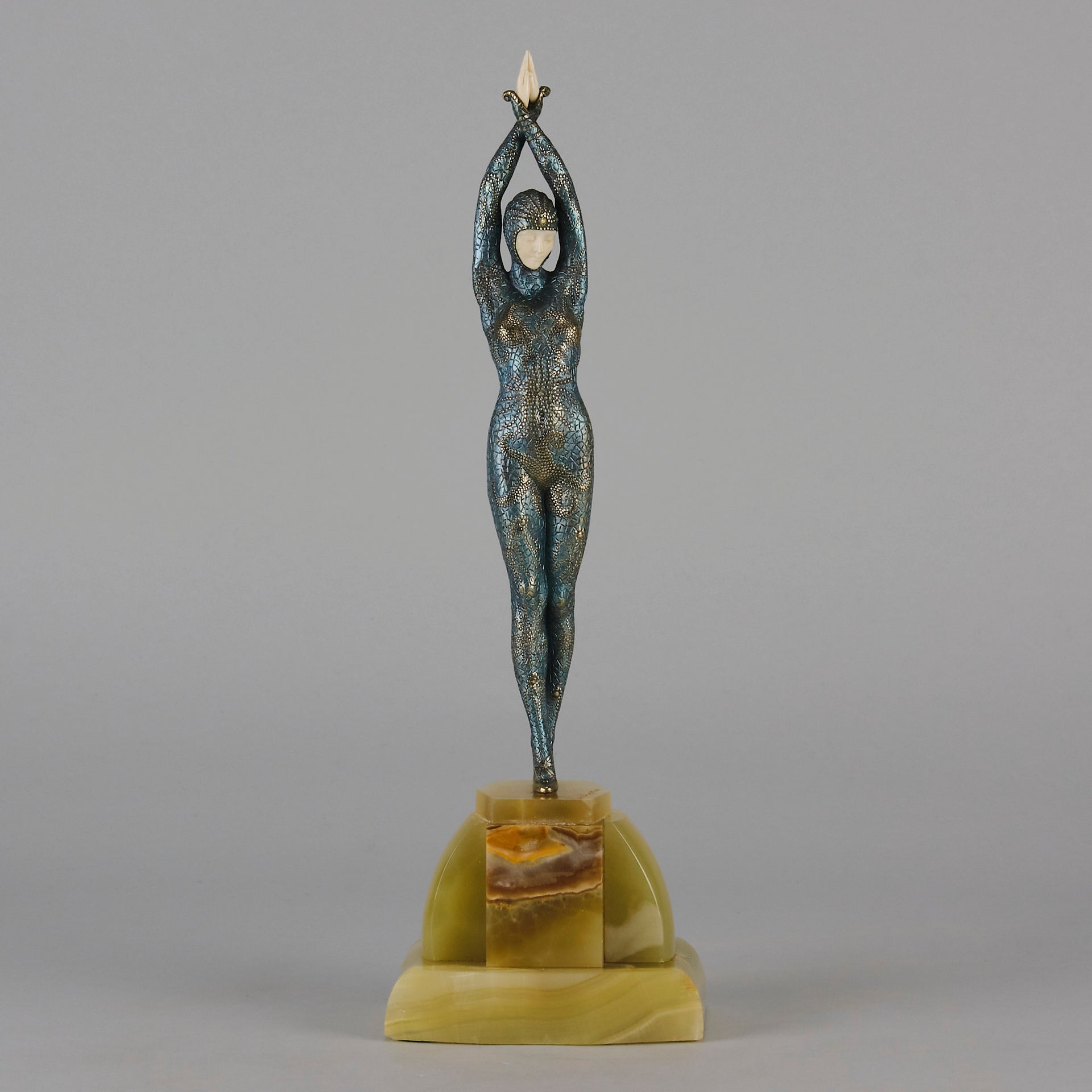  Starfish by Demetre Chiparus a  Art Deco cold painted silver and enamel bronze sculpture with ivory face and hands representing a young female Ballets Russes dancer wearing a metallic blue skin tight leotard further decorated in a bejewelled starfish pattern, modelled reaching upwards with both arms, her hands interlaced. Raised on a shaped onyx base