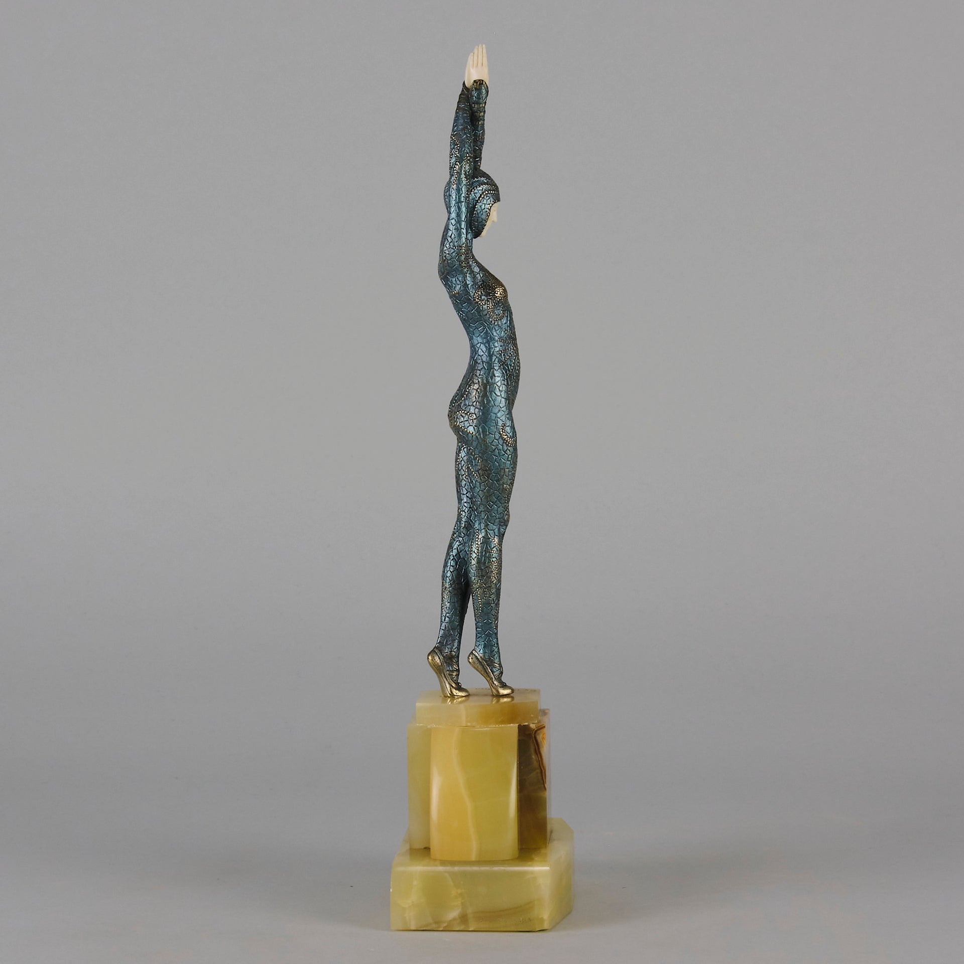  Starfish by Demetre Chiparus a  Art Deco cold painted silver and enamel bronze sculpture with ivory face and hands representing a young female Ballets Russes dancer wearing a metallic blue skin tight leotard further decorated in a bejewelled starfish pattern, modelled reaching upwards with both arms, her hands interlaced. Raised on a shaped onyx base