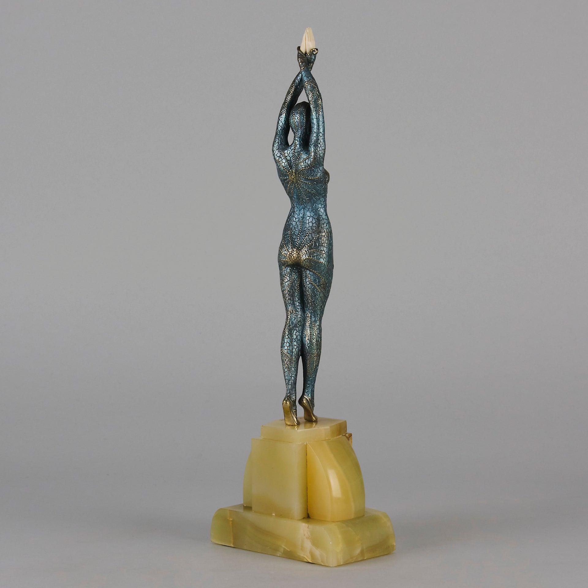  Starfish by Demetre Chiparus a  Art Deco cold painted silver and enamel bronze sculpture with ivory face and hands representing a young female Ballets Russes dancer wearing a metallic blue skin tight leotard further decorated in a bejewelled starfish pattern, modelled reaching upwards with both arms, her hands interlaced. Raised on a shaped onyx base