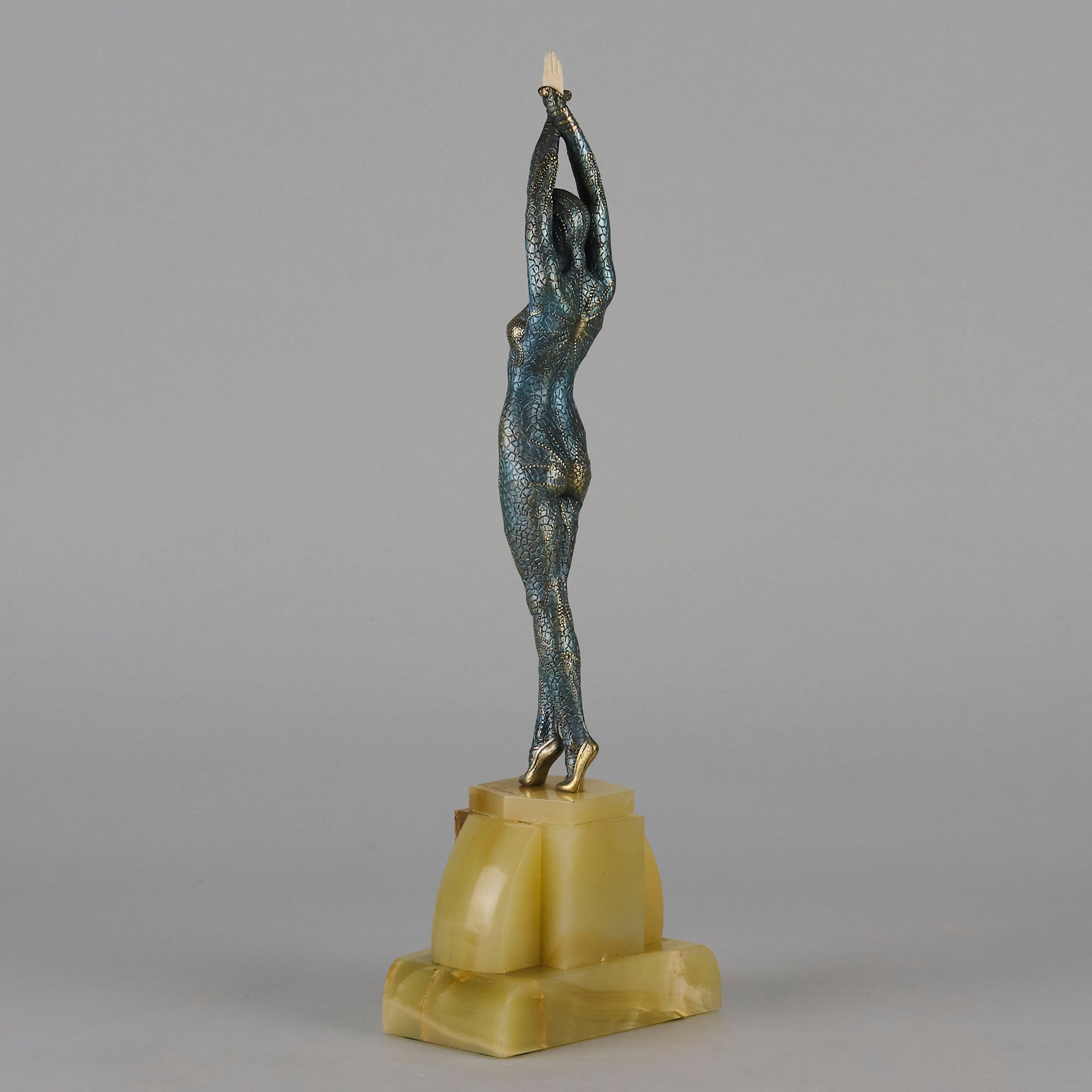  Starfish by Demetre Chiparus a  Art Deco cold painted silver and enamel bronze sculpture with ivory face and hands representing a young female Ballets Russes dancer wearing a metallic blue skin tight leotard further decorated in a bejewelled starfish pattern, modelled reaching upwards with both arms, her hands interlaced. Raised on a shaped onyx base