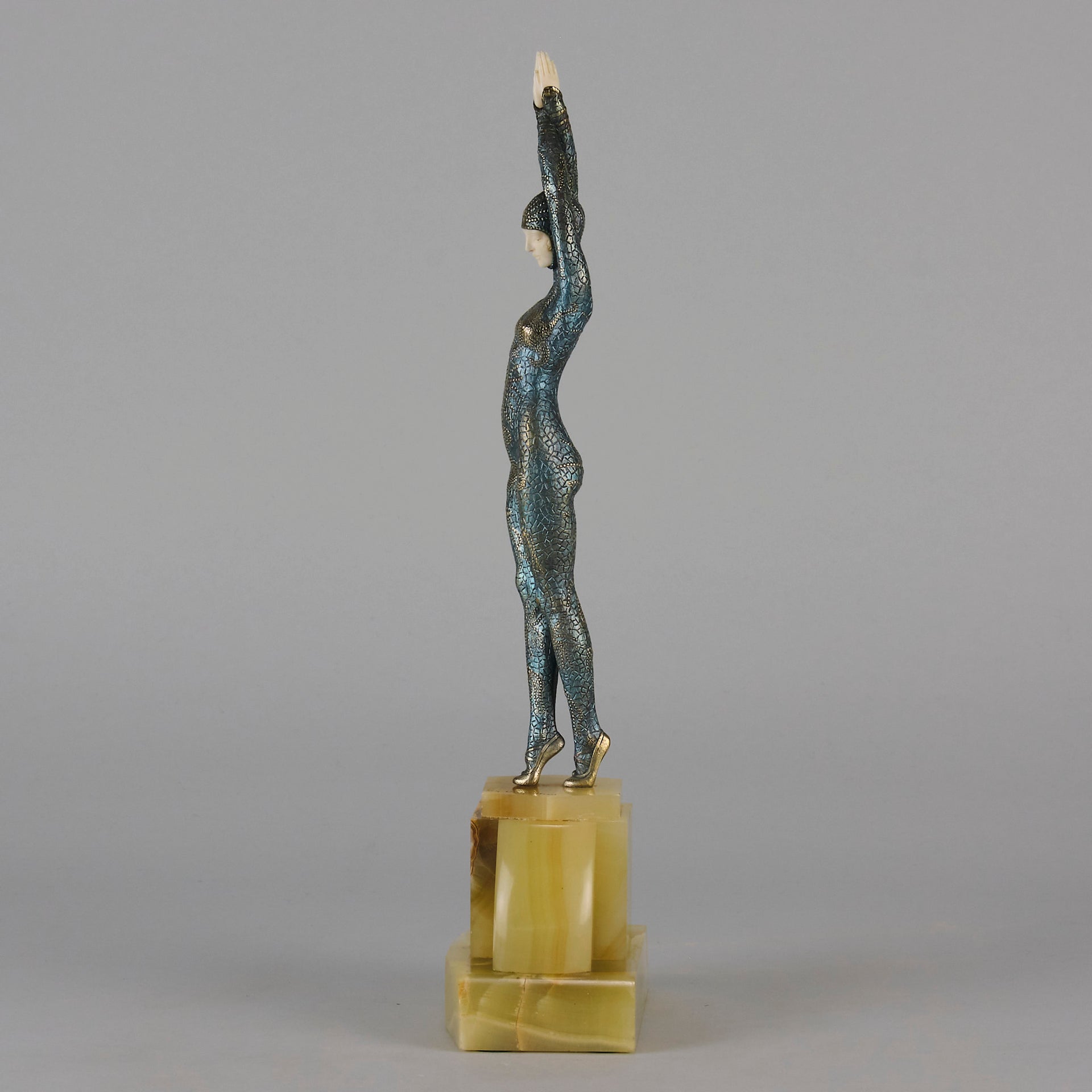  Starfish by Demetre Chiparus a  Art Deco cold painted silver and enamel bronze sculpture with ivory face and hands representing a young female Ballets Russes dancer wearing a metallic blue skin tight leotard further decorated in a bejewelled starfish pattern, modelled reaching upwards with both arms, her hands interlaced. Raised on a shaped onyx base