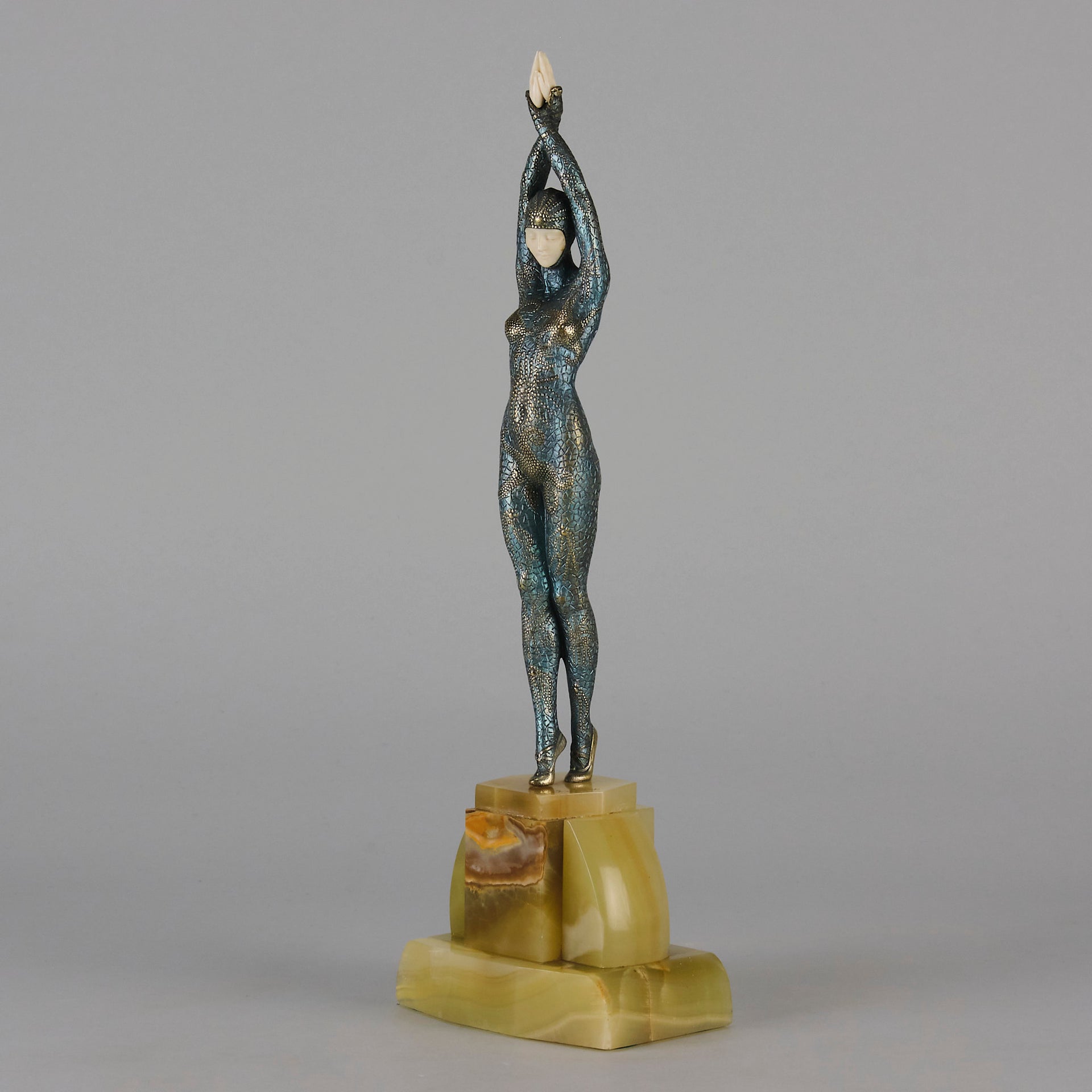  Starfish by Demetre Chiparus a  Art Deco cold painted silver and enamel bronze sculpture with ivory face and hands representing a young female Ballets Russes dancer wearing a metallic blue skin tight leotard further decorated in a bejewelled starfish pattern, modelled reaching upwards with both arms, her hands interlaced. Raised on a shaped onyx base