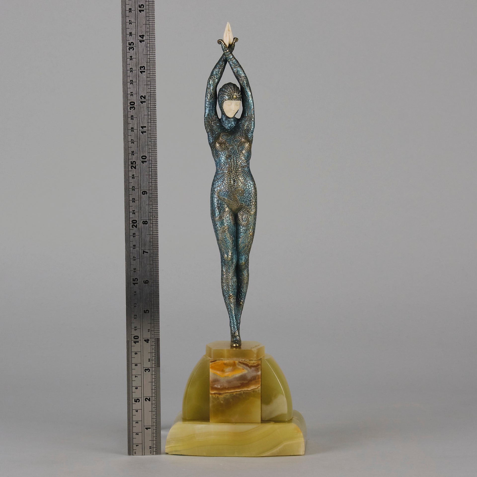  Starfish by Demetre Chiparus a  Art Deco cold painted silver and enamel bronze sculpture with ivory face and hands representing a young female Ballets Russes dancer wearing a metallic blue skin tight leotard further decorated in a bejewelled starfish pattern, modelled reaching upwards with both arms, her hands interlaced. Raised on a shaped onyx base