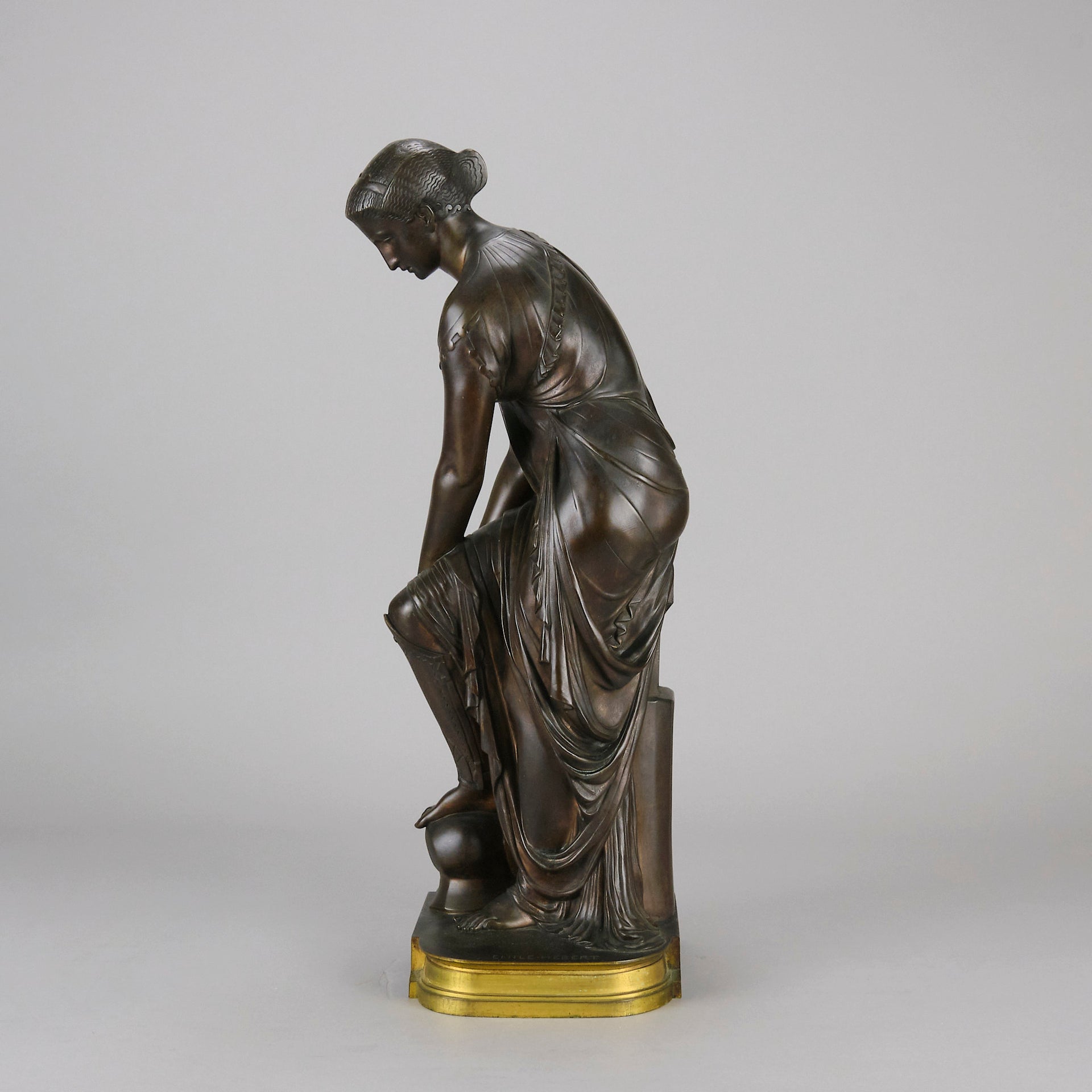 Thetis by Emile Hébert - a French late 19th Century bronze, of a striking female warrior figure known as Thetis the Greek Goddess of War. She is adjusting her shin guards in preparation for her next opponent, whilst sitting on an anvil. Raised on top of a partly gilded base