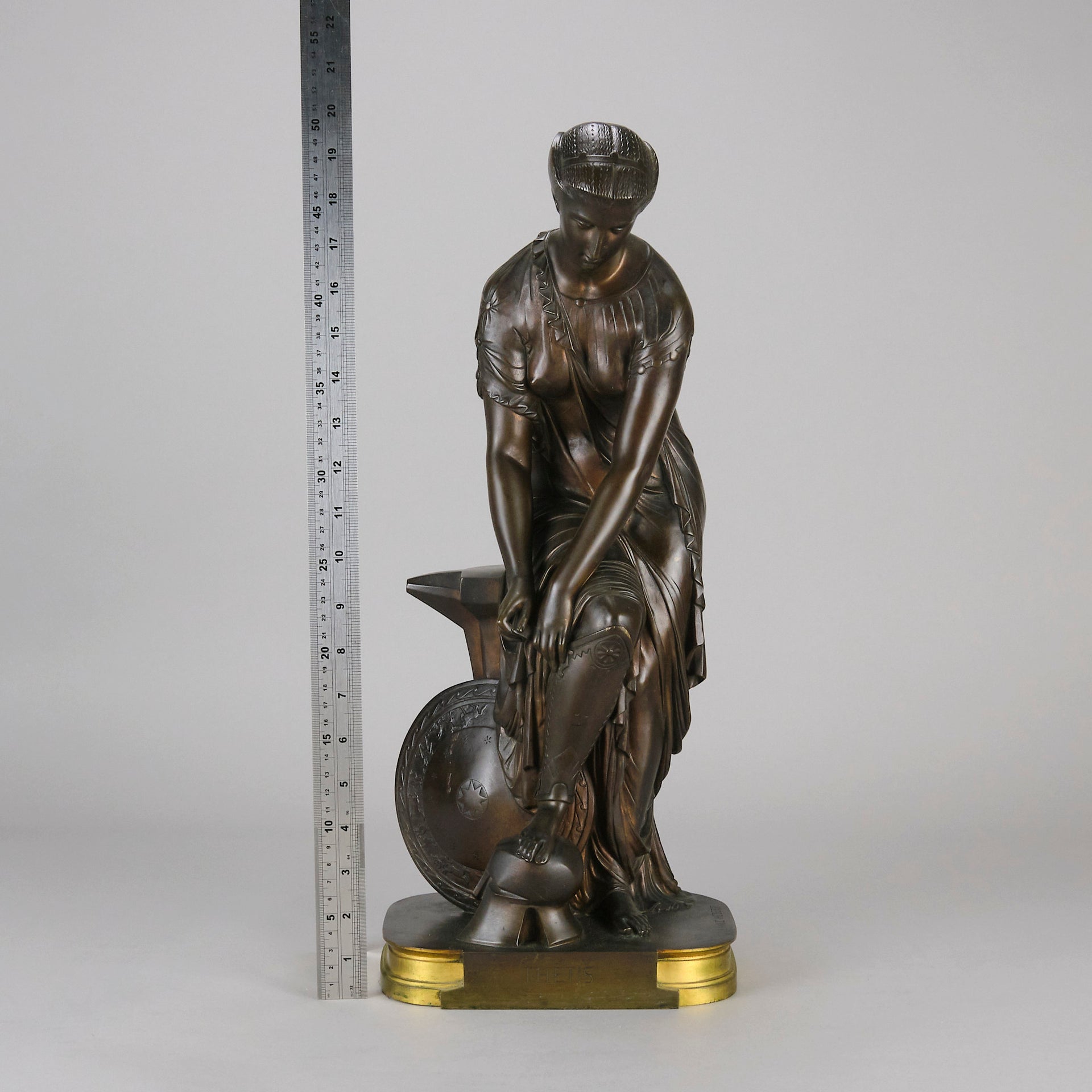 Thetis by Emile Hébert - a French late 19th Century bronze, of a striking female warrior figure known as Thetis the Greek Goddess of War. She is adjusting her shin guards in preparation for her next opponent, whilst sitting on an anvil. Raised on top of a partly gilded base