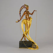 Pleasures of the Courtesan by Erté an attractive limited edition 20th Century bronze figure modelled as a beautiful young woman holding a long golden chain from a treasure chest at her feet wearing only an flamboyant skirt & headdress