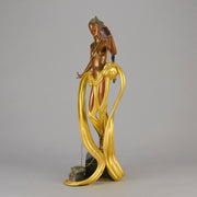 Pleasures of the Courtesan by Erté an attractive limited edition 20th Century bronze figure modelled as a beautiful young woman holding a long golden chain from a treasure chest at her feet wearing only an flamboyant skirt & headdress