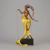 Pleasures of the Courtesan by Erté an attractive limited edition 20th Century bronze figure modelled as a beautiful young woman holding a long golden chain from a treasure chest at her feet wearing only an flamboyant skirt & headdress