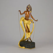 Pleasures of the Courtesan by Erté an attractive limited edition 20th Century bronze figure modelled as a beautiful young woman holding a long golden chain from a treasure chest at her feet wearing only an flamboyant skirt & headdress