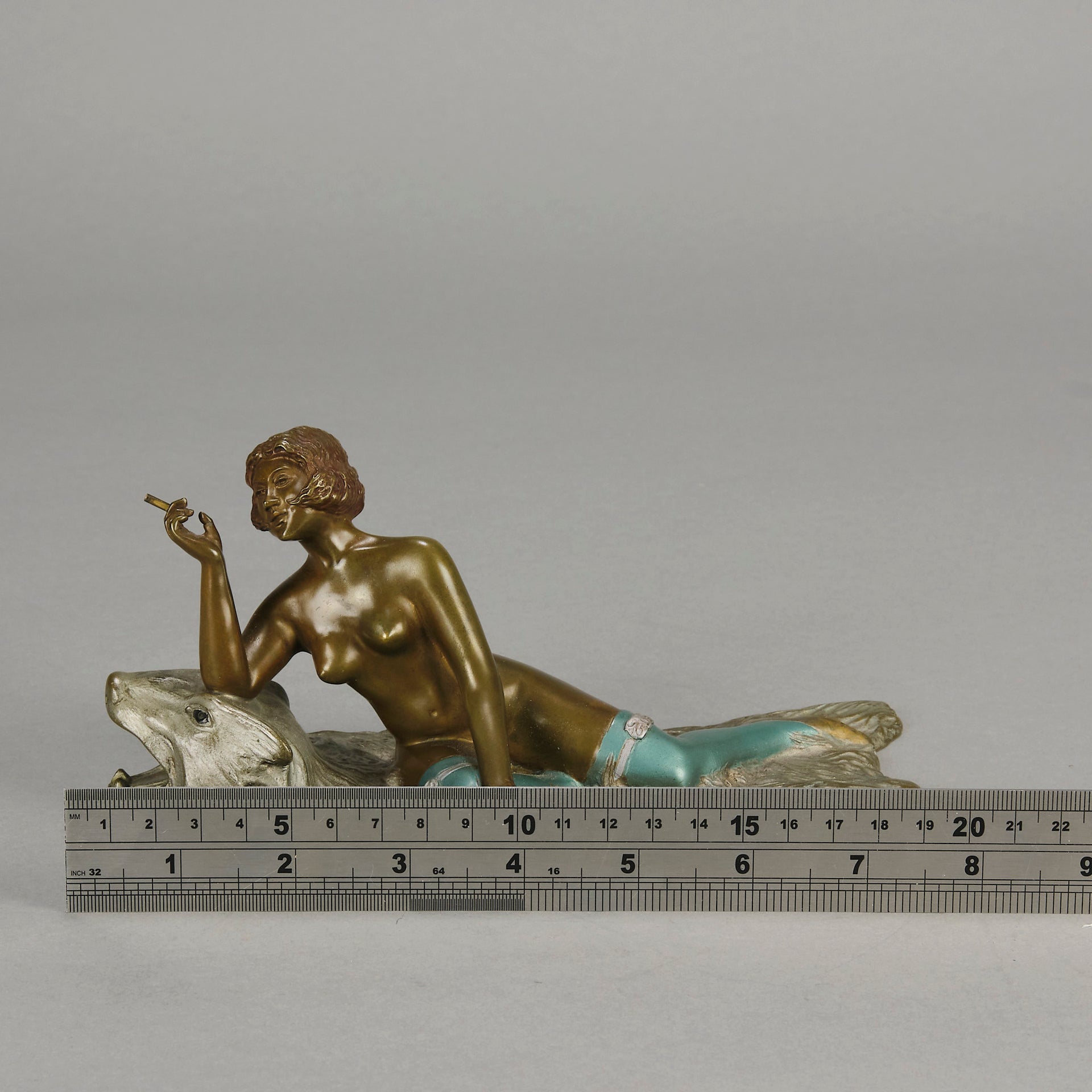 Lady on Bear Skin by Toni Fiedler an attractive early 20th Century bronze study of a lady wearing only a pair of stockings and heals seductively laying on a bear skin rug whilst smoking a cigarette