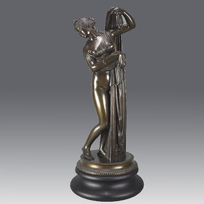 Callipygian Venus an Antique Bronze Figure depicting a partially draped woman, raising her light peplos (draped clothing) to uncover her hips and buttocks, and looking back and down over her shoulder
