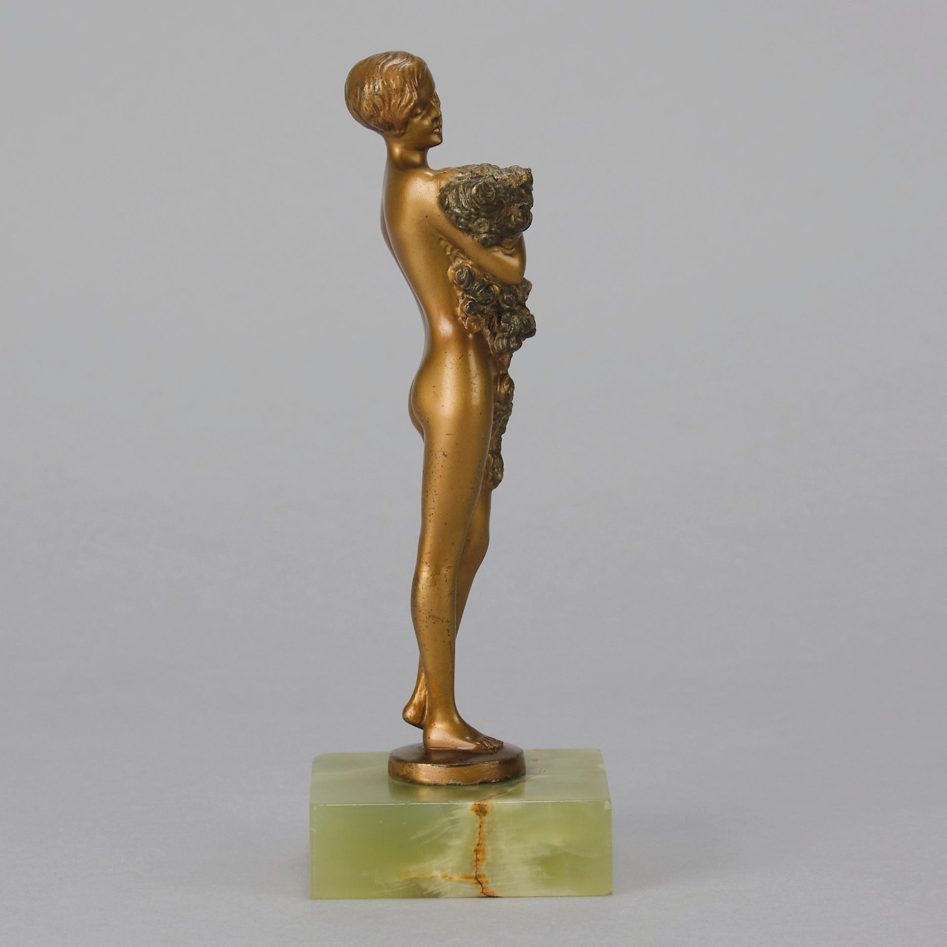 The Bouquet by Joseph Lorenzl an elegant early 20th Century Art Deco cold painted bronze figure of a young beauty holding a large bouquet of flowers covering her modesty raised on a green onyx base 