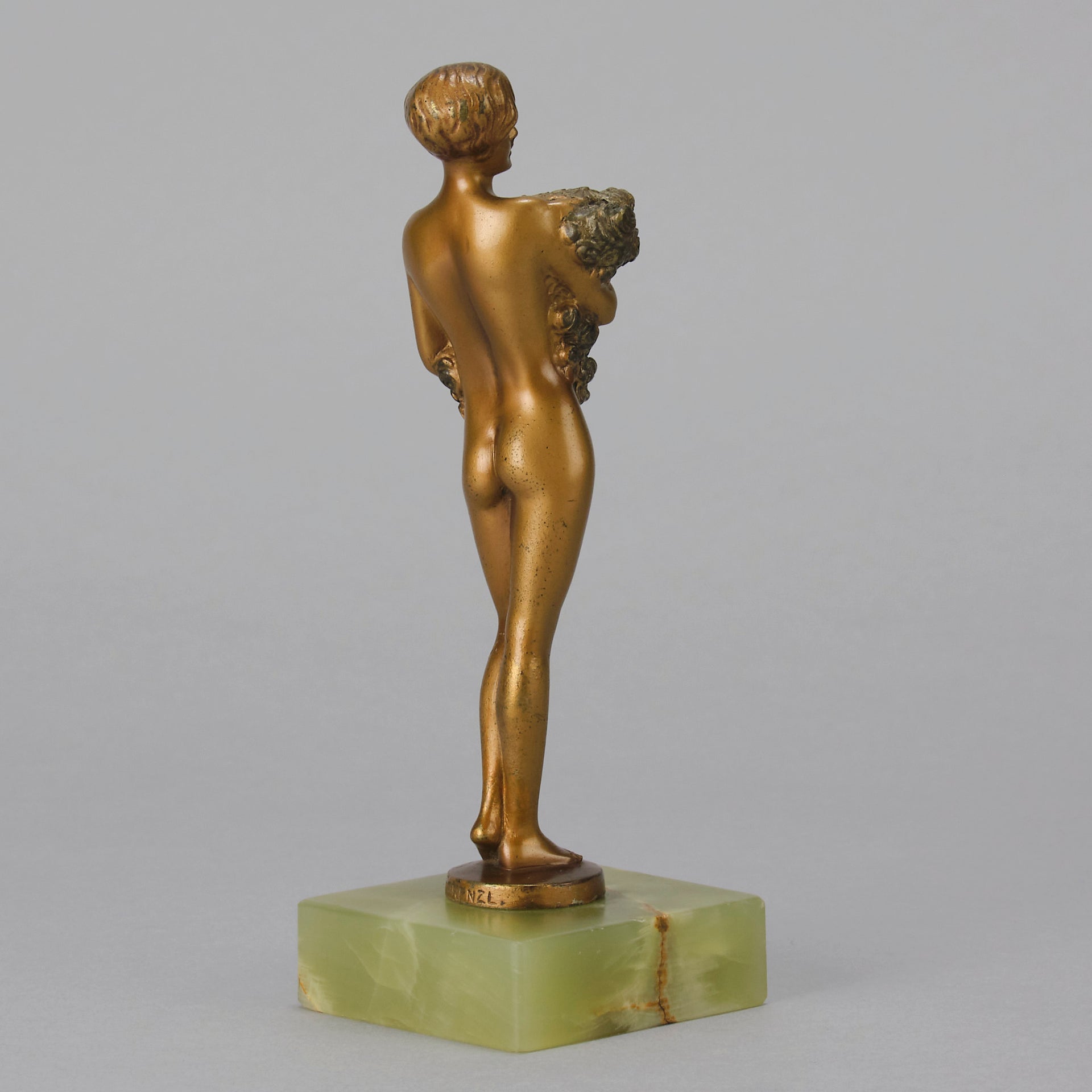 The Bouquet by Joseph Lorenzl an elegant early 20th Century Art Deco cold painted bronze figure of a young beauty holding a large bouquet of flowers covering her modesty raised on a green onyx base 