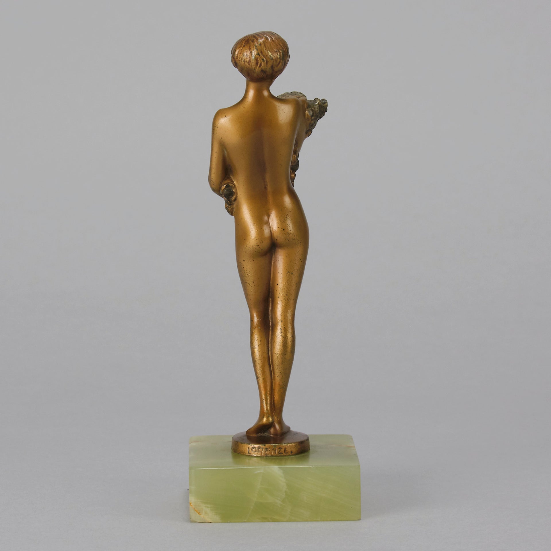 The Bouquet by Joseph Lorenzl an elegant early 20th Century Art Deco cold painted bronze figure of a young beauty holding a large bouquet of flowers covering her modesty raised on a green onyx base 