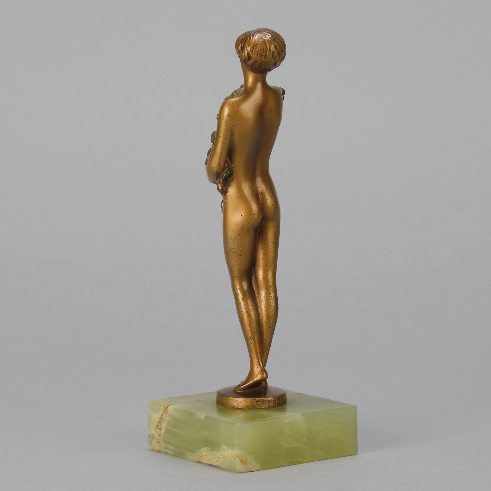 The Bouquet by Joseph Lorenzl an elegant early 20th Century Art Deco cold painted bronze figure of a young beauty holding a large bouquet of flowers covering her modesty raised on a green onyx base 