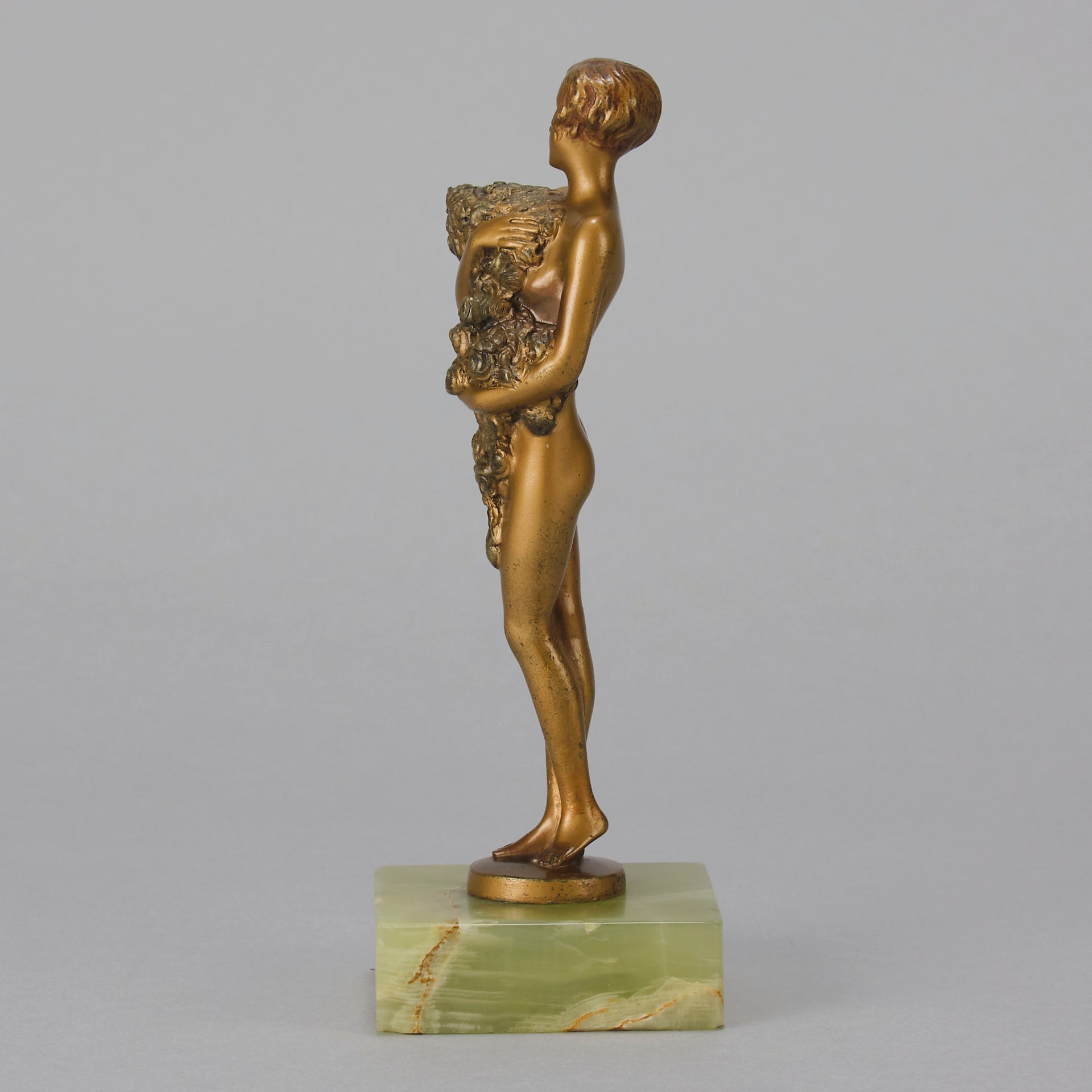 The Bouquet by Joseph Lorenzl an elegant early 20th Century Art Deco cold painted bronze figure of a young beauty holding a large bouquet of flowers covering her modesty raised on a green onyx base 