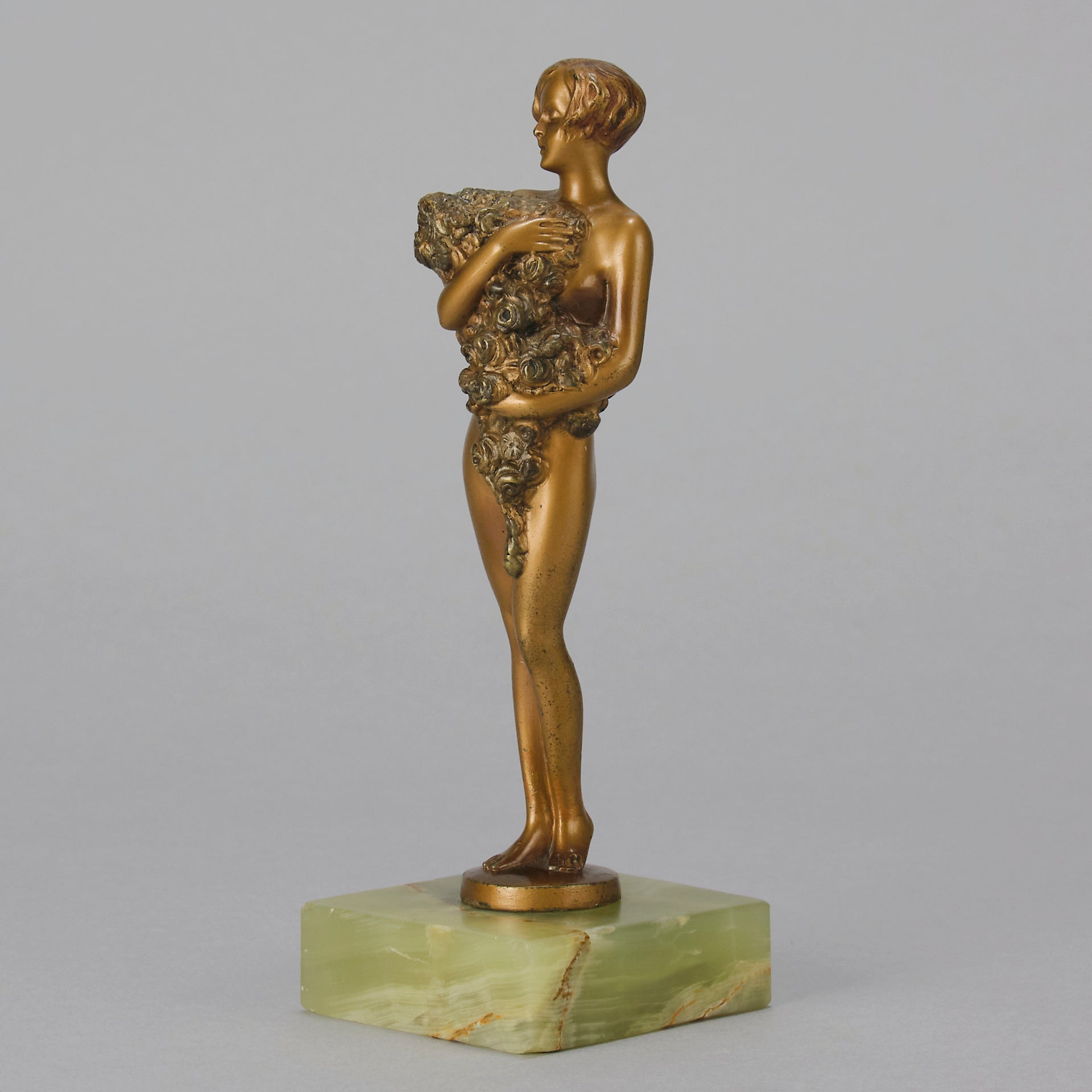 The Bouquet by Joseph Lorenzl an elegant early 20th Century Art Deco cold painted bronze figure of a young beauty holding a large bouquet of flowers covering her modesty raised on a green onyx base 