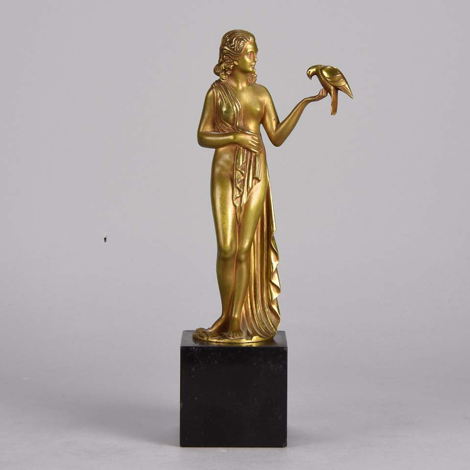 Femme avec Oiseau by Pierre Laurel an antique bronze figure of a semi clad young woman holding a bird in classic high Art Deco pose with excellent gilt patination and intricate surface detail on a square shaped black marble base 