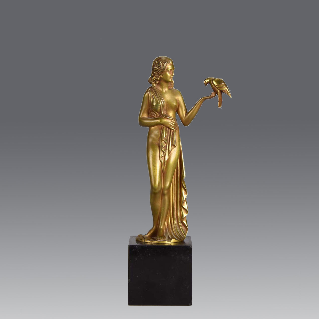 Femme avec Oiseau by Pierre Laurel an antique bronze figure of a semi clad young woman holding a bird in classic high Art Deco pose with excellent gilt patination and intricate surface detail on a square shaped black marble base 