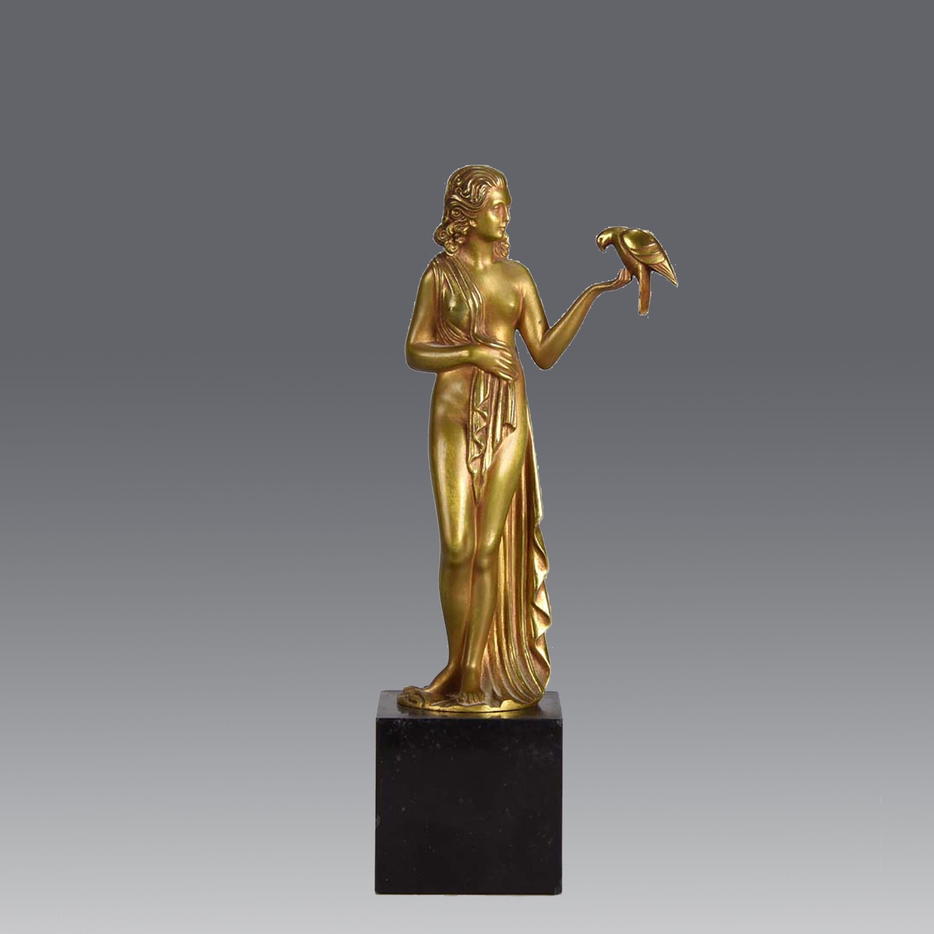 Femme avec Oiseau by Pierre Laurel an antique bronze figure of a semi clad young woman holding a bird in classic high Art Deco pose with excellent gilt patination and intricate surface detail on a square shaped black marble base 
