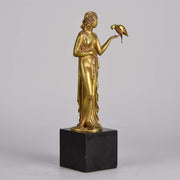 Femme avec Oiseau by Pierre Laurel an antique bronze figure of a semi clad young woman holding a bird in classic high Art Deco pose with excellent gilt patination and intricate surface detail on a square shaped black marble base 