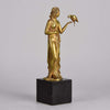 Femme avec Oiseau by Pierre Laurel an antique bronze figure of a semi clad young woman holding a bird in classic high Art Deco pose with excellent gilt patination and intricate surface detail on a square shaped black marble base 