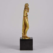 Femme avec Oiseau by Pierre Laurel an antique bronze figure of a semi clad young woman holding a bird in classic high Art Deco pose with excellent gilt patination and intricate surface detail on a square shaped black marble base 