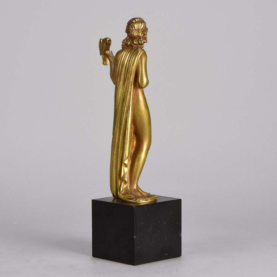 Femme avec Oiseau by Pierre Laurel an antique bronze figure of a semi clad young woman holding a bird in classic high Art Deco pose with excellent gilt patination and intricate surface detail on a square shaped black marble base 