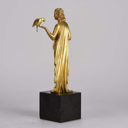 Femme avec Oiseau by Pierre Laurel an antique bronze figure of a semi clad young woman holding a bird in classic high Art Deco pose with excellent gilt patination and intricate surface detail on a square shaped black marble base 
